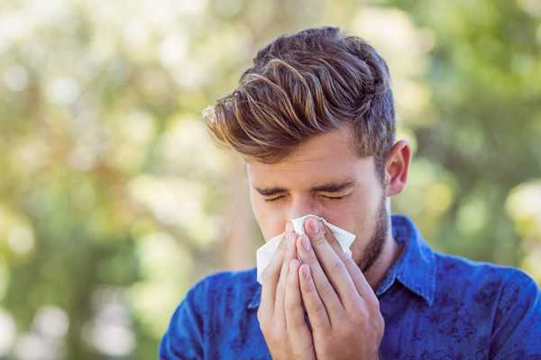 Young man holding nose and sneezing from terrible allergies