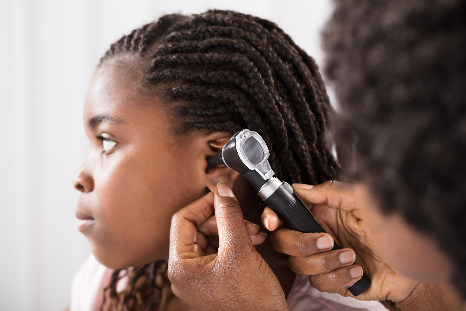 Doctor checking little girl's ear canal with an otoscope.