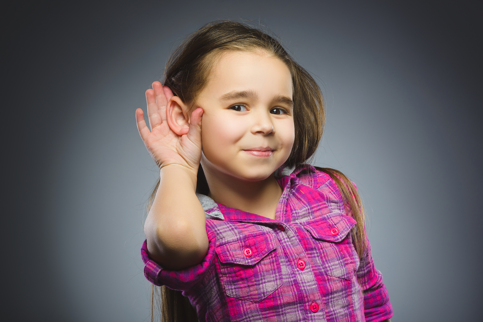 LIttle girl cupping her hand behind her ear to hear better.