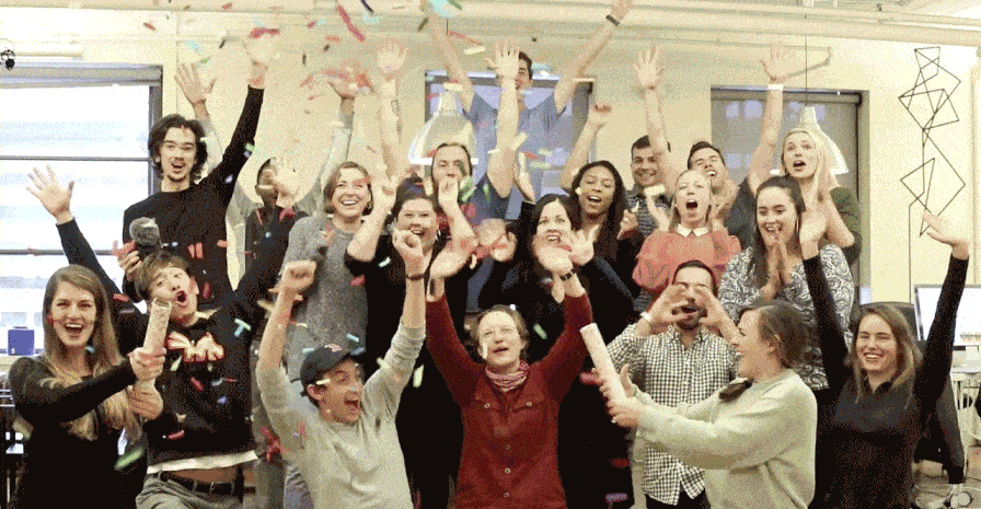 This is a gif of SaaS company employees waving and cheering as confetti falls from above