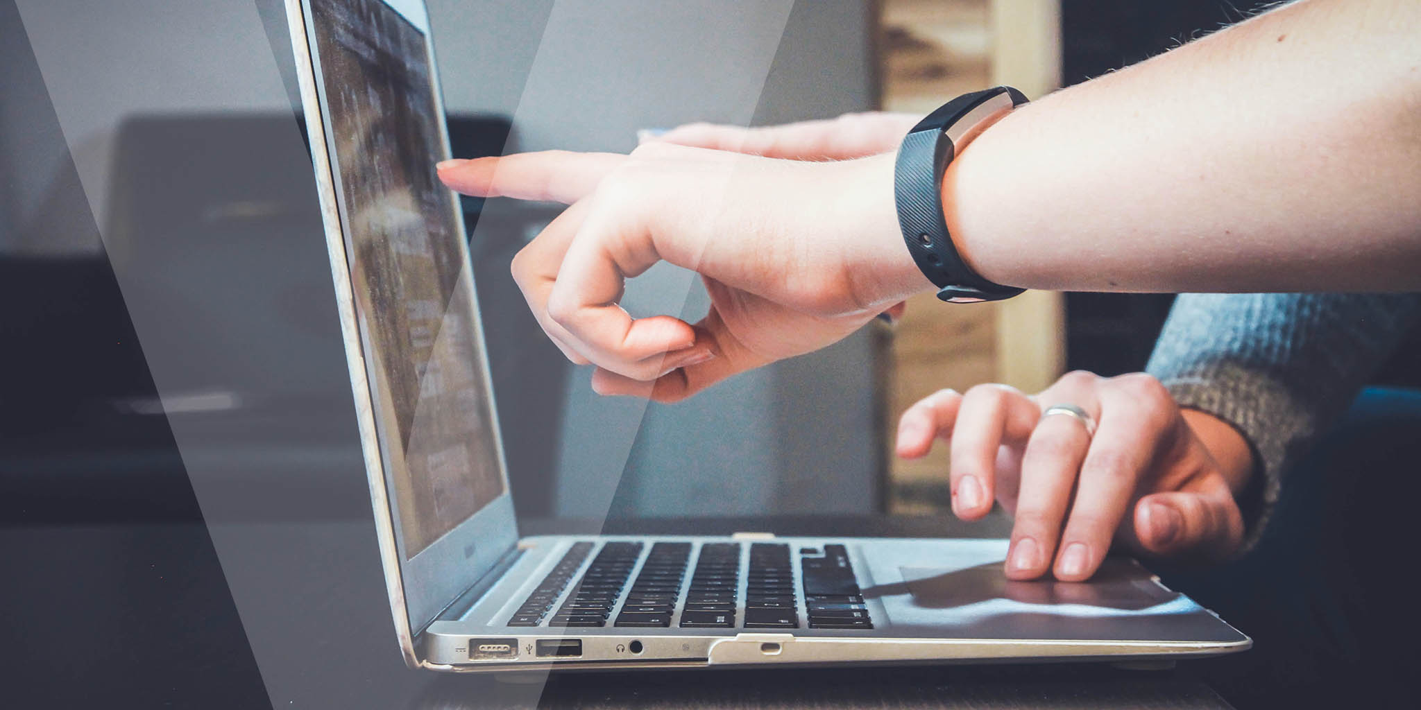 Close up image of a laptop with people pointing at the screen