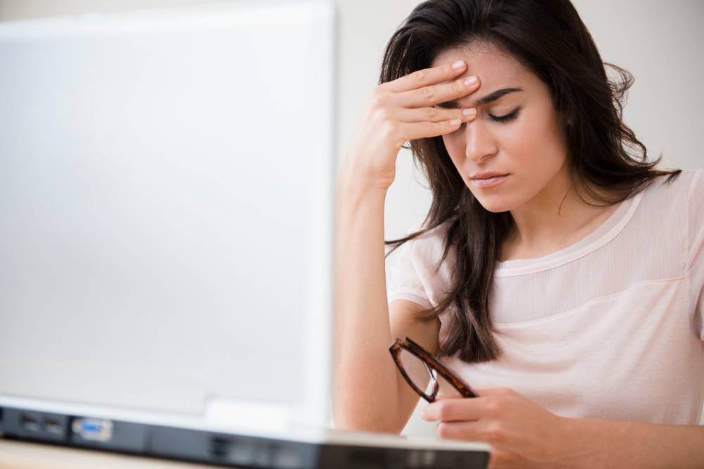 A woman feeling tensed sitting in front of her laptop