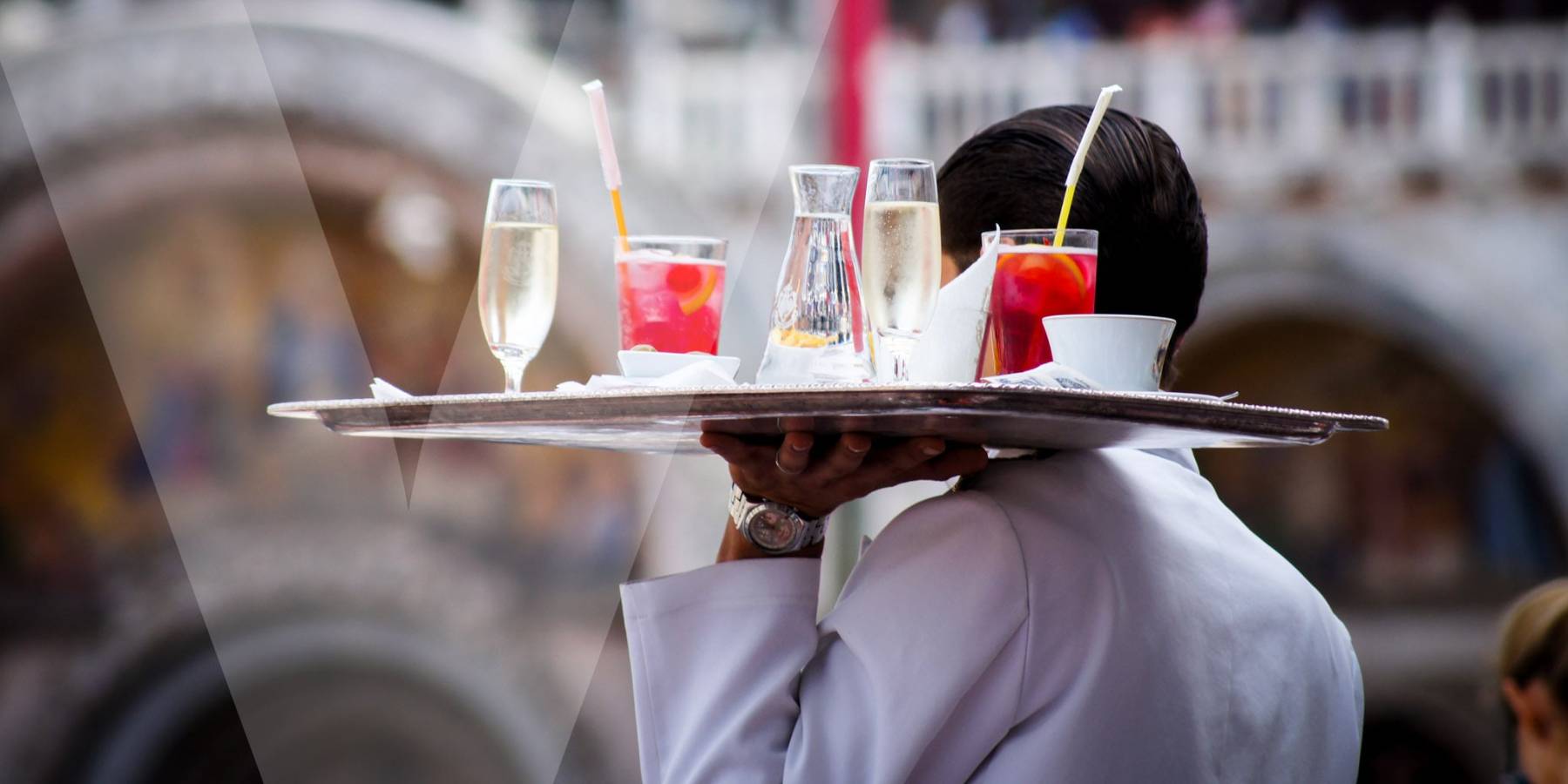 A waiter carrying a service plate full of beverages