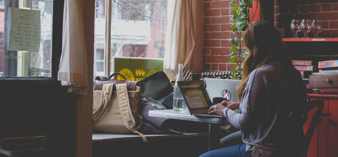 A person working at a laptop in a coffee house