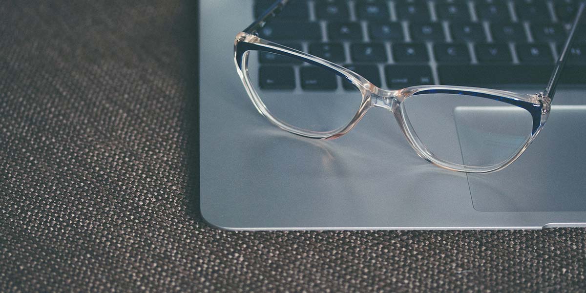 A pair of glasses resting on a laptop