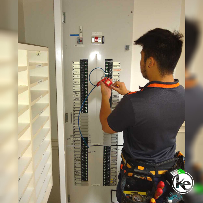 Licensed electrician doing electrical compliance testing on commercial switchboard