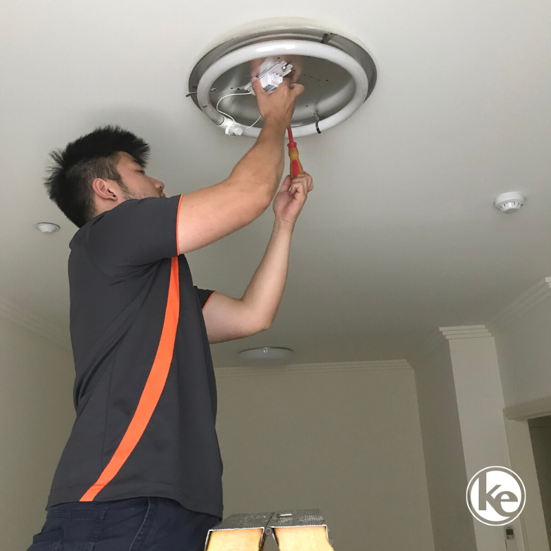 Reliable electrician installing a new LED oyster light