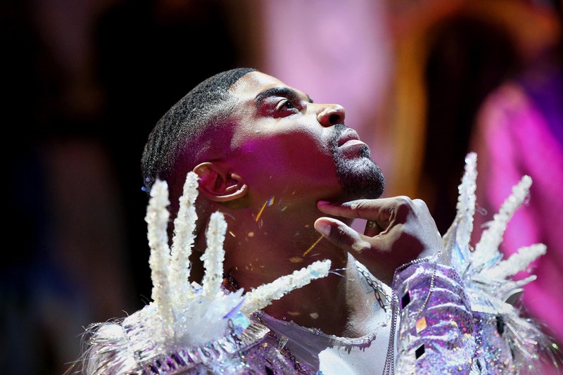 a Black ballroom performer looks up while wearing an elaborate sparkly outfit.
