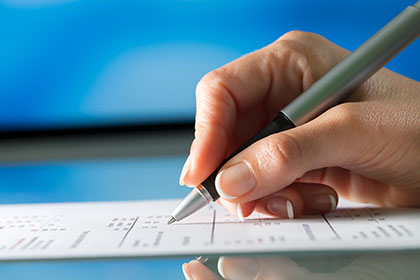 Hand with a pen filling out a form