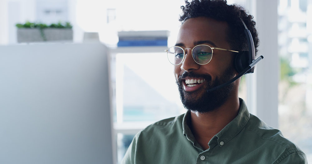 A technology consultant wearing a headset and assisting a company on the phone.