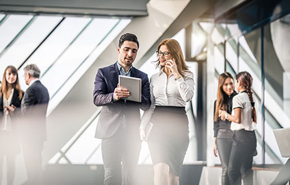 Coworkers walking next to each other while reviewing compensation and benefits documents.