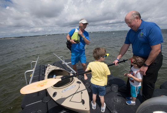 Santa Rosa County Commissioner Dave Piech helps Kelvin and Kyle Hall as the two youngsters help out Dave Barker, who is putting his kayak into the water at the Navarre Beach Marine Park on Tuesday.