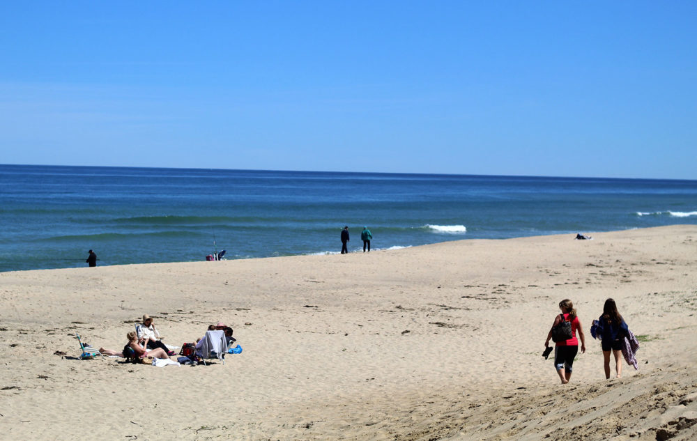 Two people walk along Newcomb Hollow Beach in Wellfleet. (Quincy Walters/WBUR)
