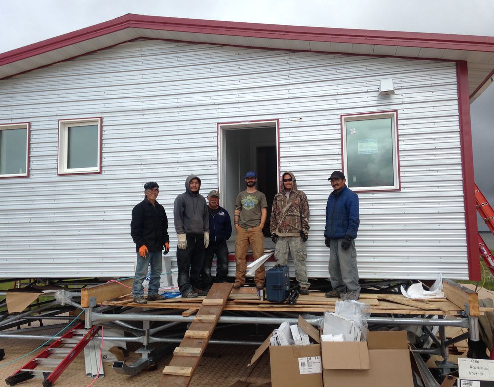 Aaron Cooke, in T-shirt and blue hat, in front of an efficient house he helped design after he and Newtok residents built it at the new village site of Mertarvik in 2016. (Photo by Molly Rettig)