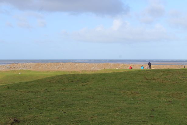 Golfers playing on Royal North Devon Golf Club's 9th hole with the new wall in the background.