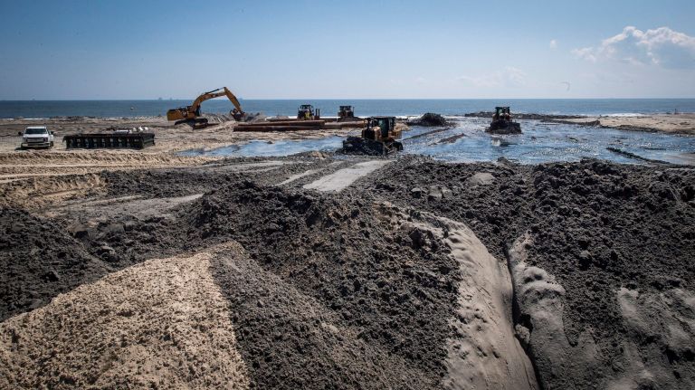 Heavy equipment moves sand as it is being