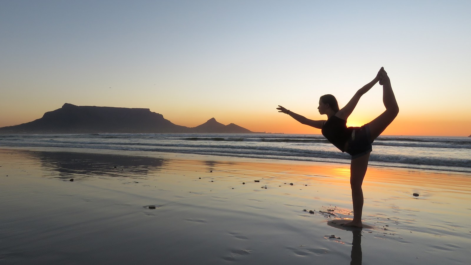 a woman does yoga on the beach