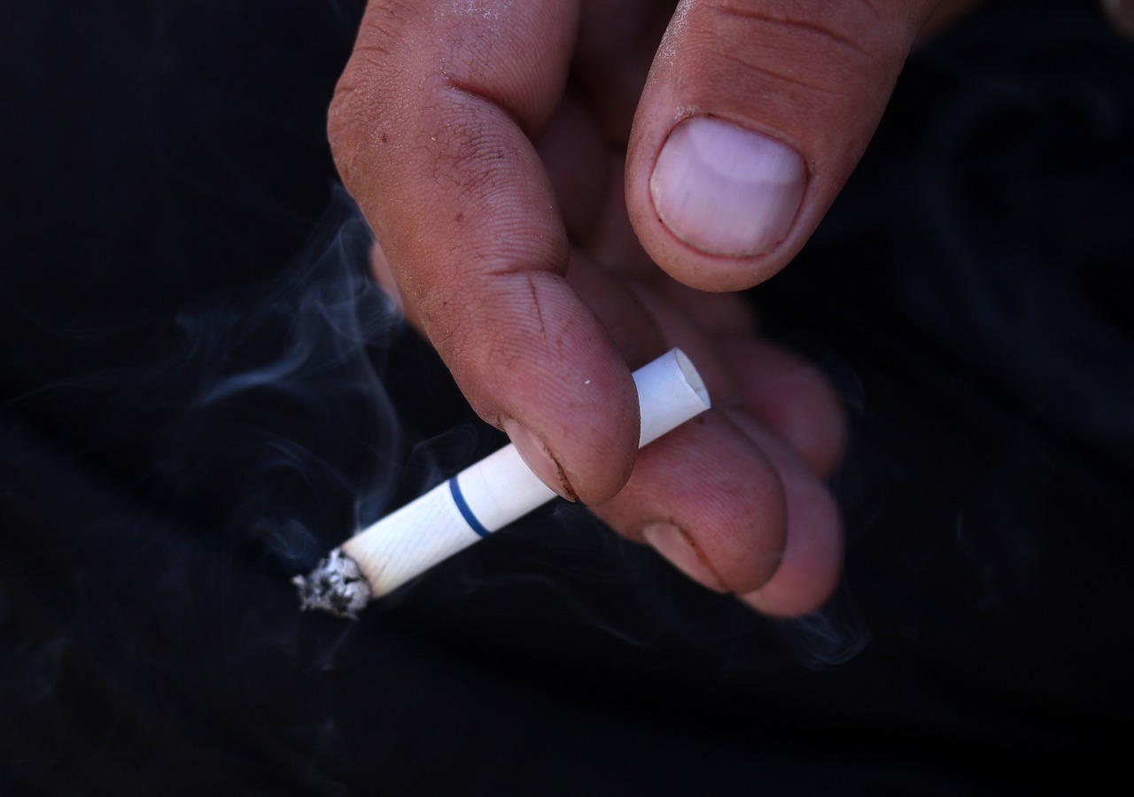 hand holding lit cigarette while smoking