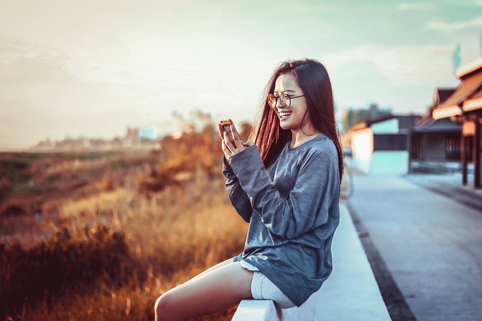 Woman sitting outside on her phone smiling