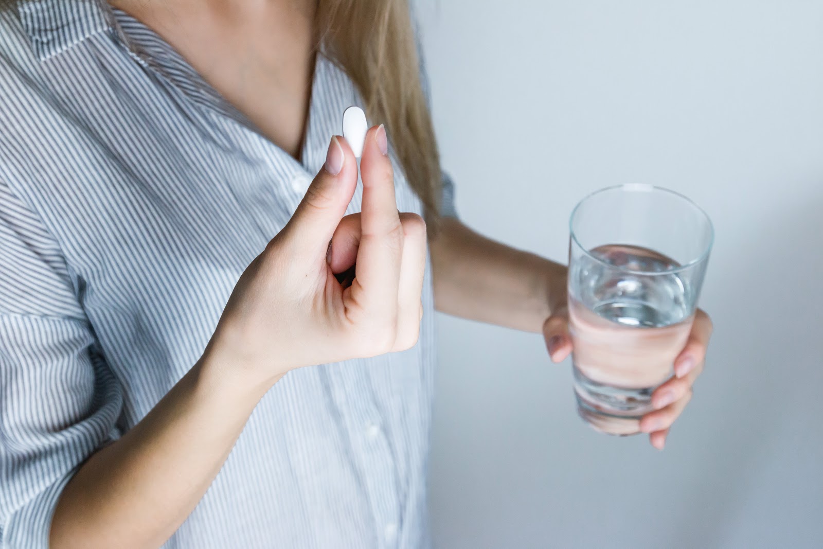 Woman preparing to study a pill with a glass of water