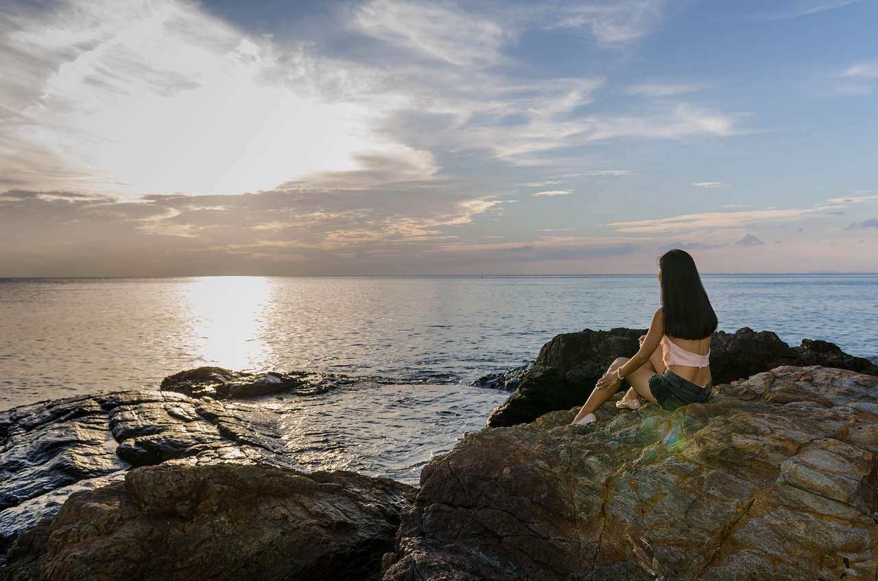 Girl sitting on rock looking at the ocean
