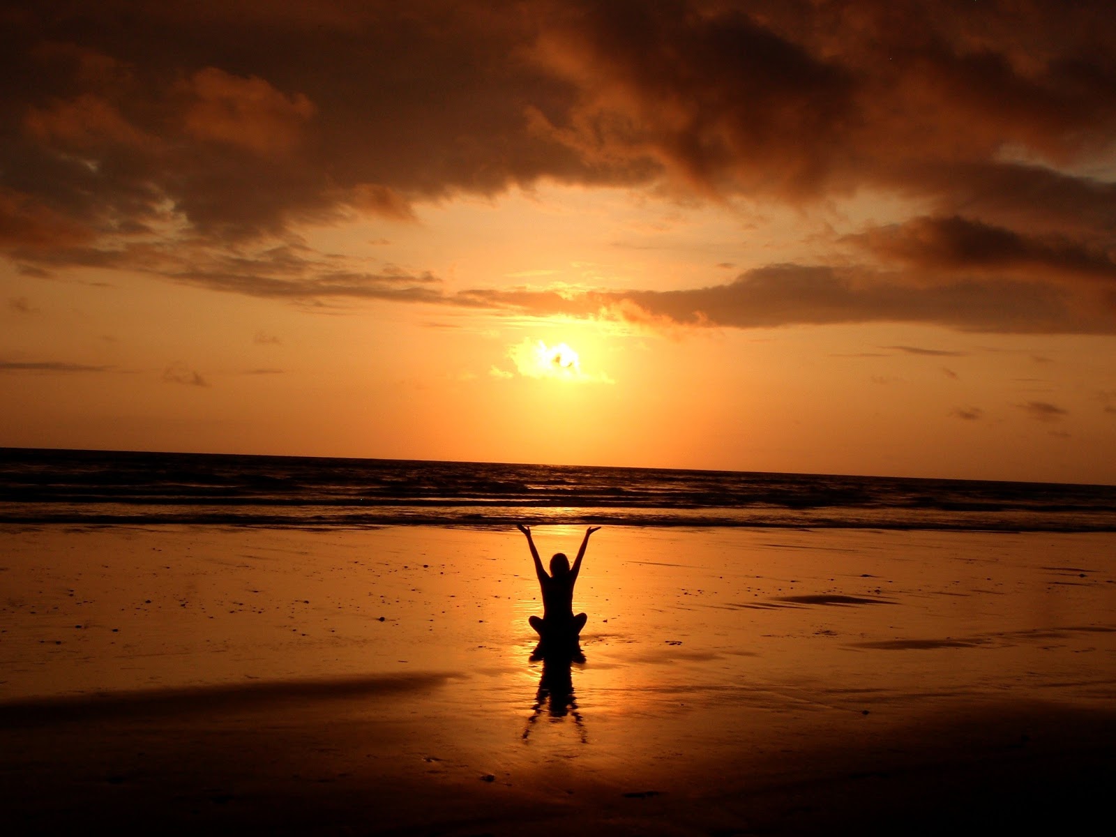 person sitting on the beach at sunset