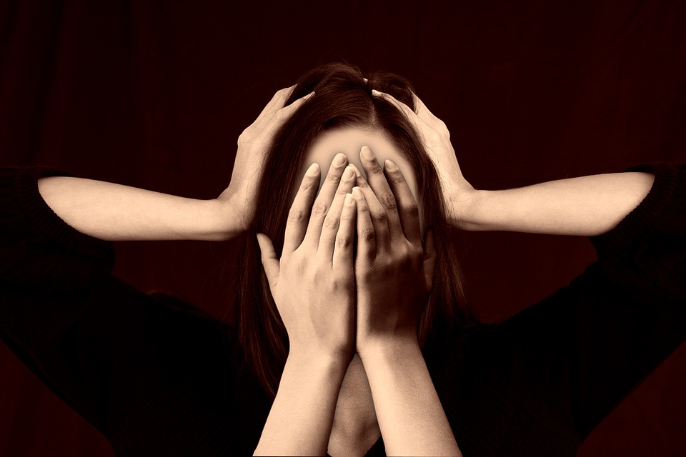 Woman holds head in pain with multiple sets of hands