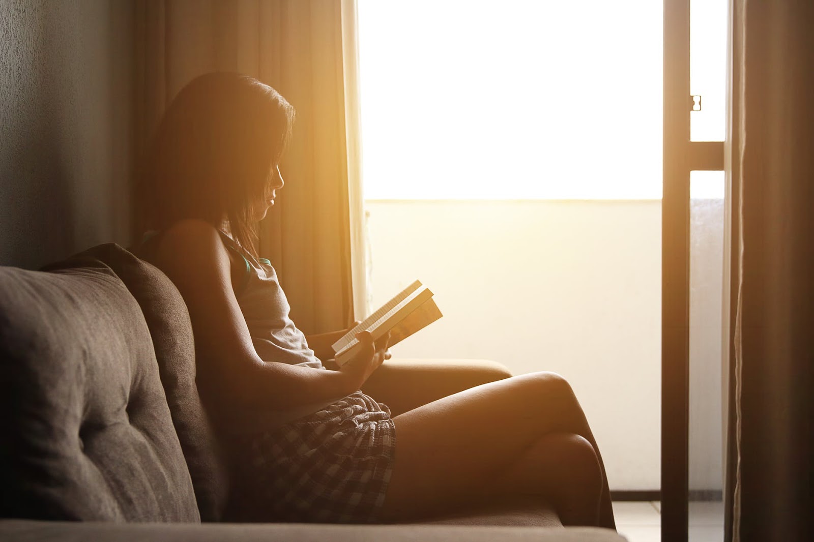 A girl enjoys her alone time while reading by a window