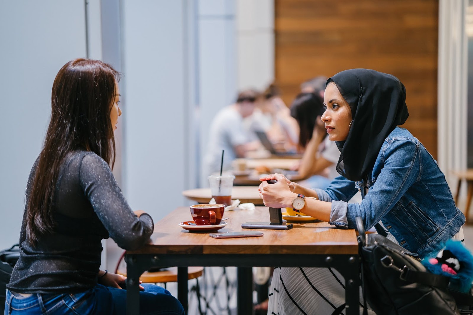 Two women sitting across from each other at a table discussing their most recent relationship struggles.