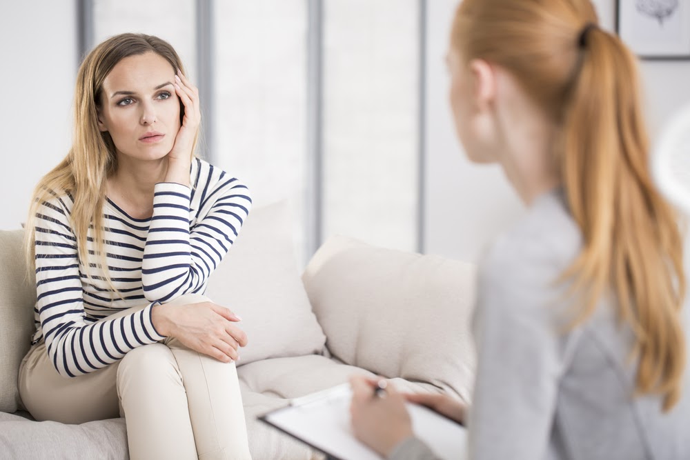 A blonde woman sits across from her therapist and listens to her give professional advice.