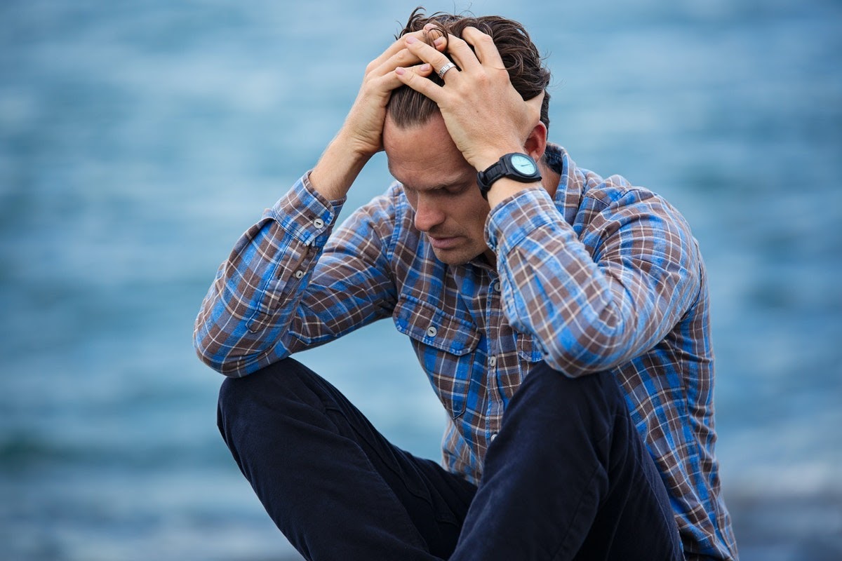A man sits appearing to be stressed, something that can easily happen as a result of losing a loved one.