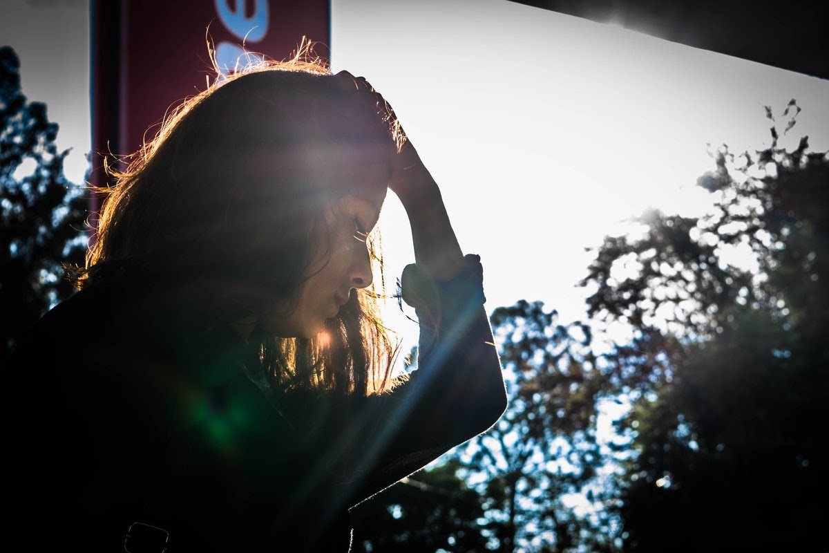 A woman stands with her hand on her head, appearing to suffer from depression or anxiety, which can have an effect on your memory.