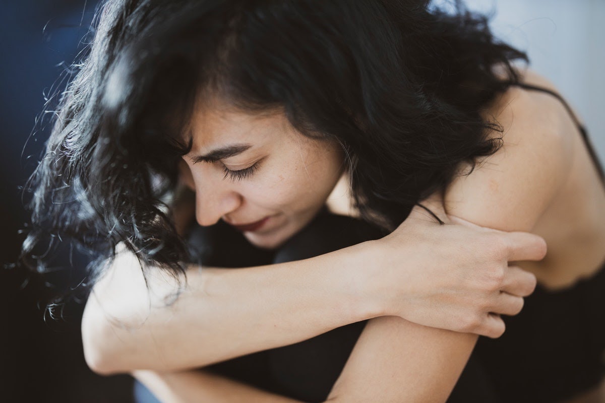 A woman sits with her arms wrapped around herself appearing to be afraid. Sometimes we can be threatened by things that aren't actually threatening when we overgeneralize.