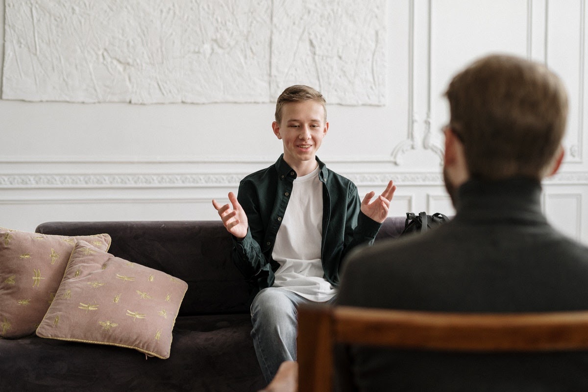 A young man appears to be having a positive conversation with his therapist.