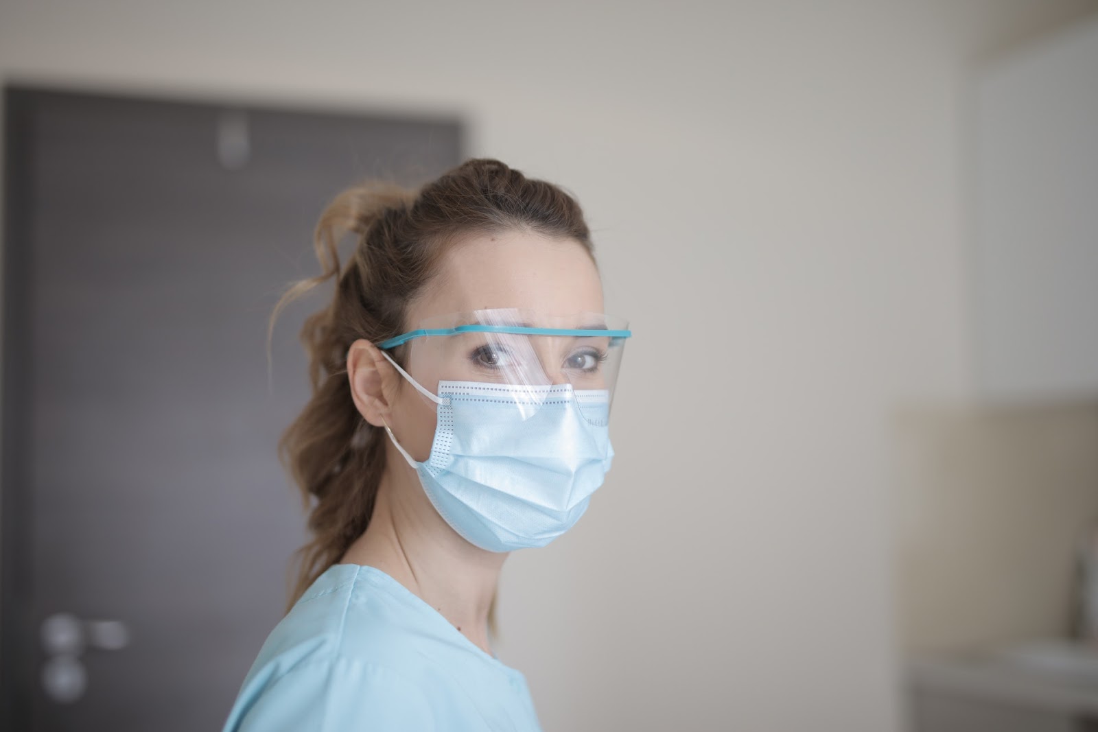 A healthcare worker wears a face shield and surgical mask, which are considered to be proper PPE for protection against COVID-19.
