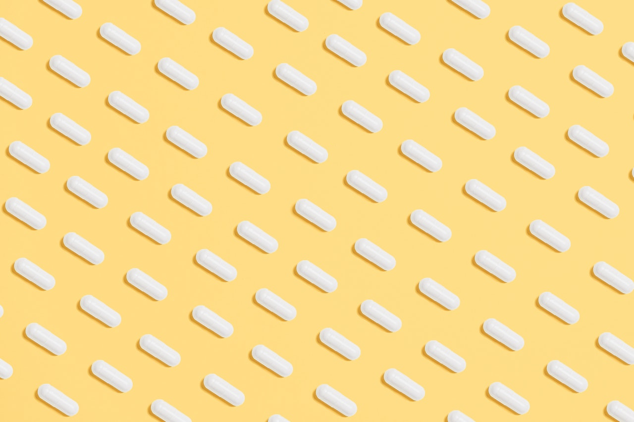 White pills are organized in rows against a yellow background.