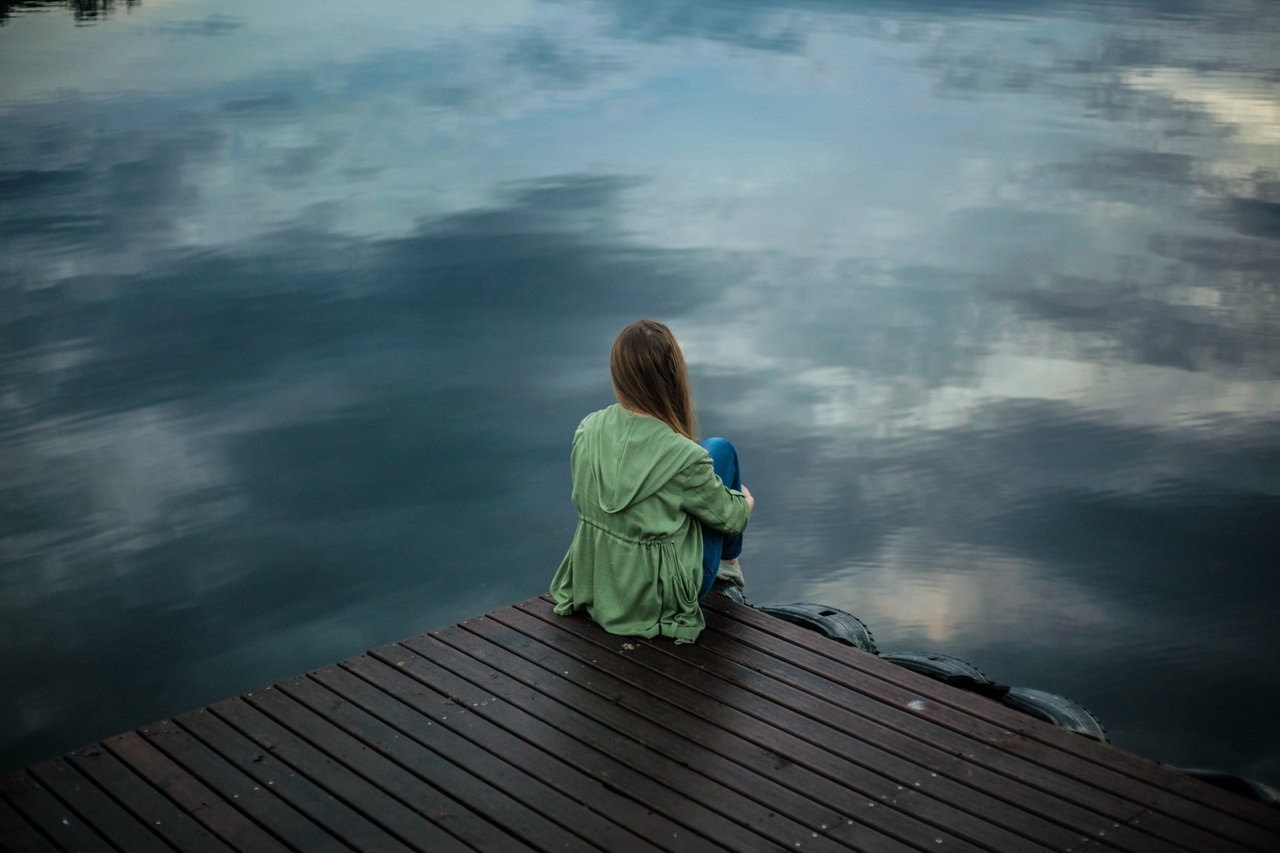 Girl sitting alone on a pier