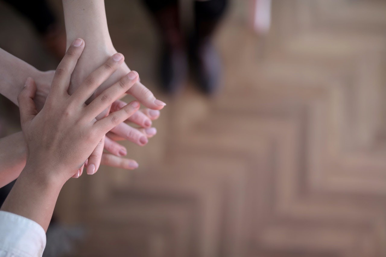 A set of hands rests on top of each other to represent support and unity.