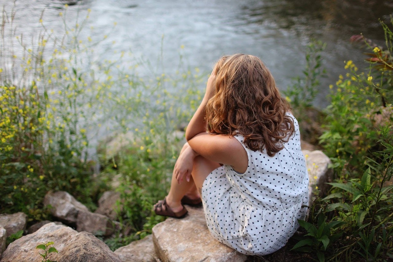 Girl stares sadly at lake