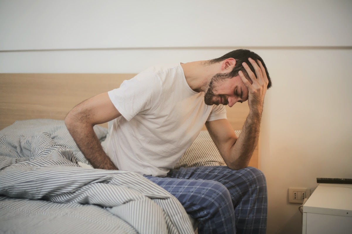 Depressed man in bed considering TMS therapy