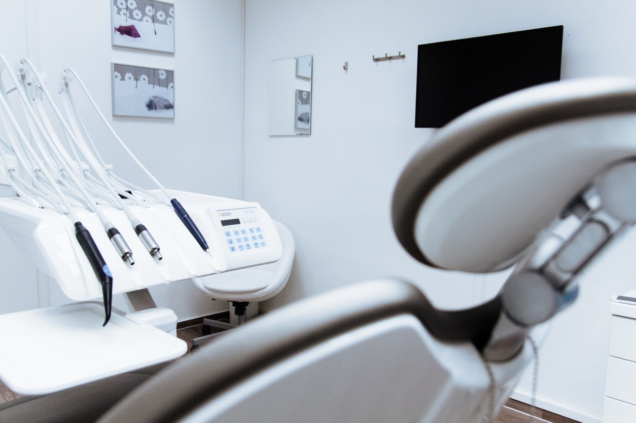 A bright white medical room with medical chair and medical equipment
