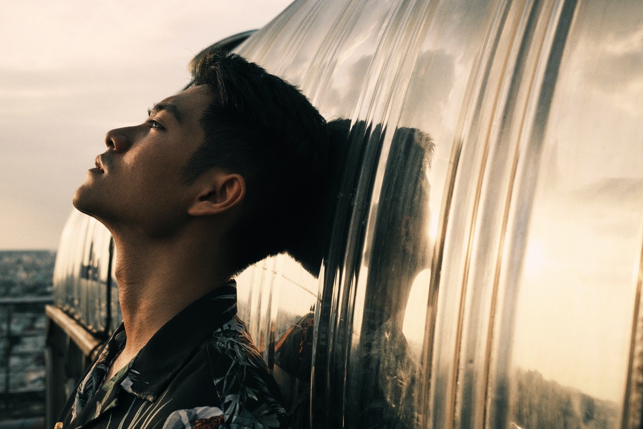Young man tilts head back against wall and stares off into the distance with a worried look