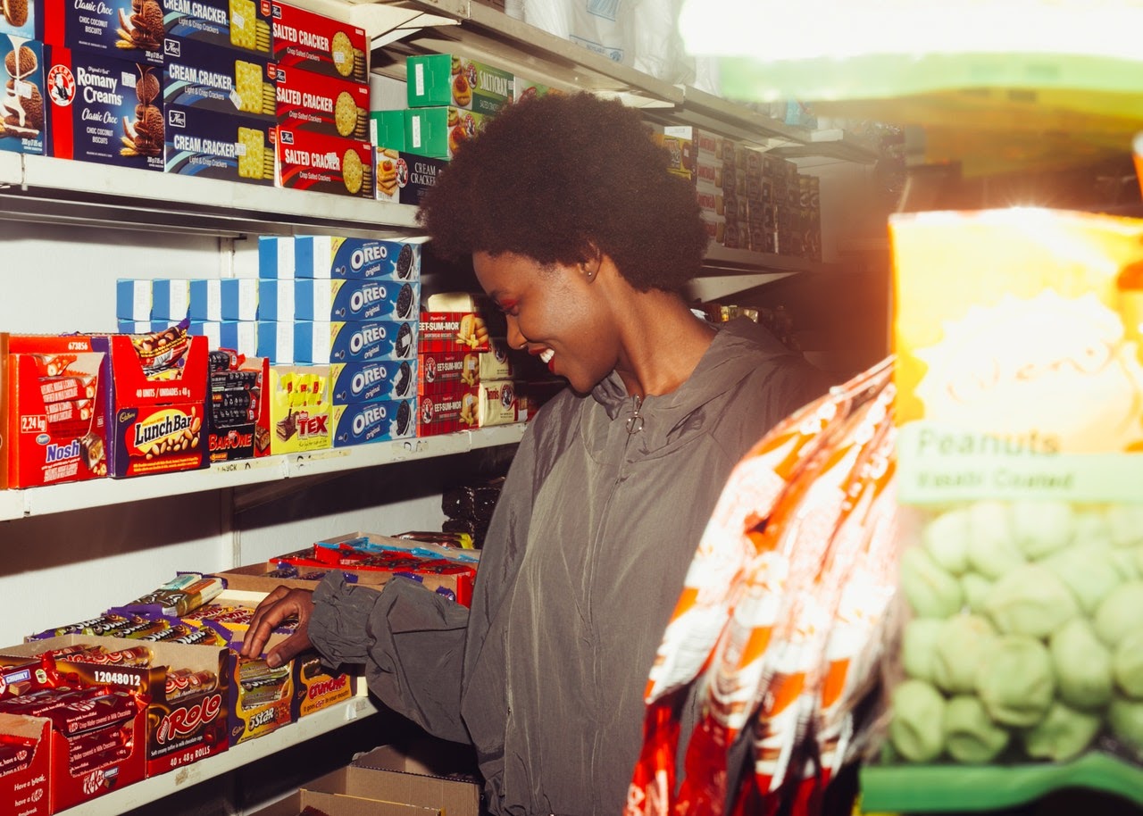 Excited woman smiles and shops through chocolate bars in a convenience store
