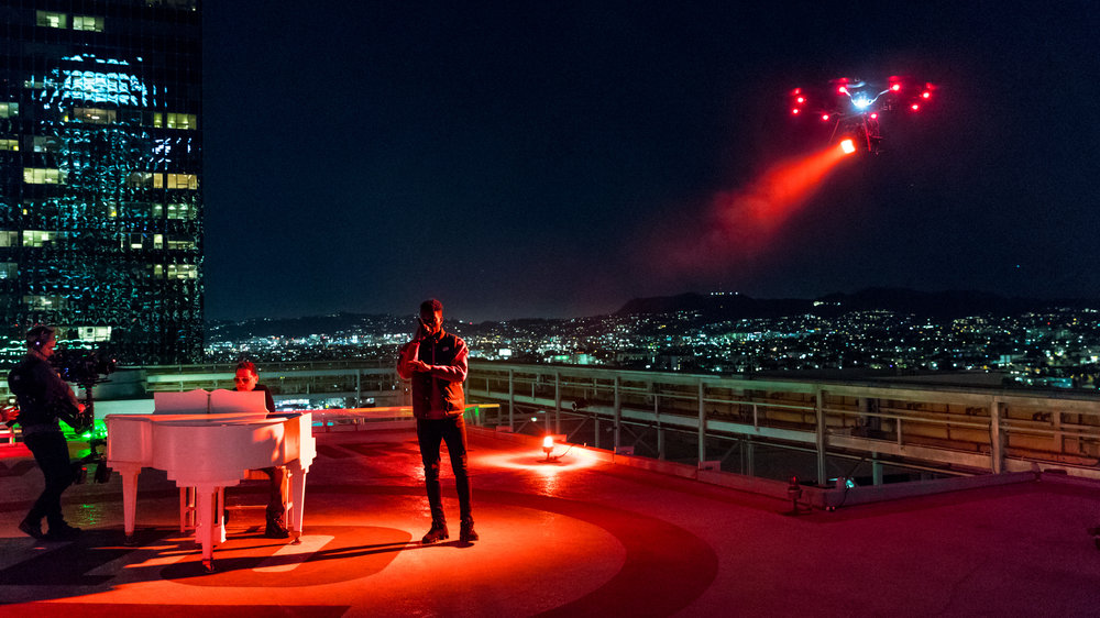 A drone lights up the helipad for Thutmose (vocals) and Storch (piano). A steadicam moves in to capture the magic of the moment. Photo Credit: Jeffrey Moustache