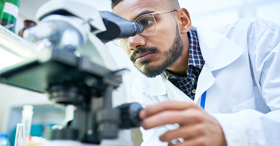 scientist looking through microscope