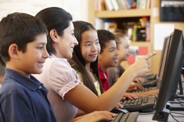 Des enfants regardent attentivement une tablette dans une salle de classe.