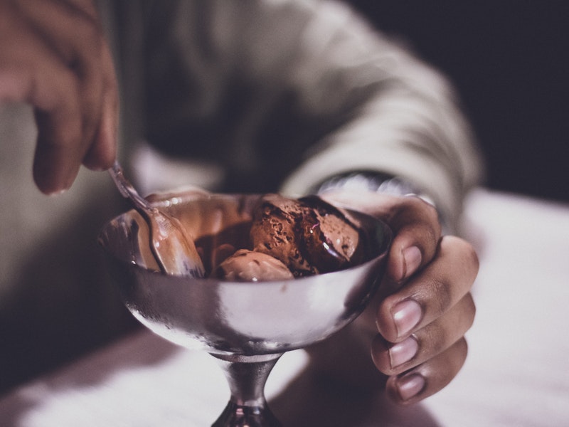 A man digs his spoon into a bowl of chocolate ice cream.