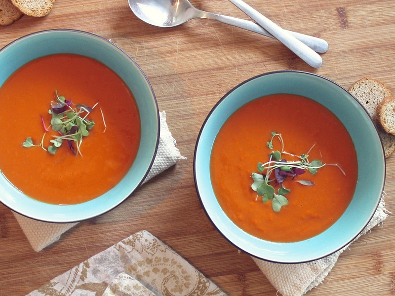 Two bowls of tomato soup, garnished with parsley, are shown here.
