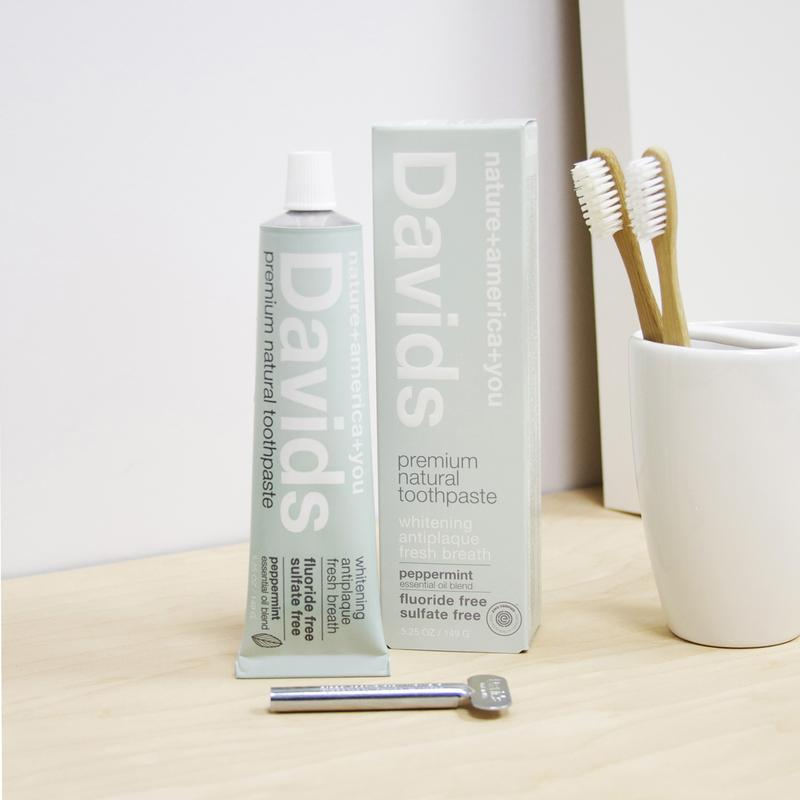 A gray box and a gray tube of Davids toothpaste sit on a counter next to a toothbrush holder.