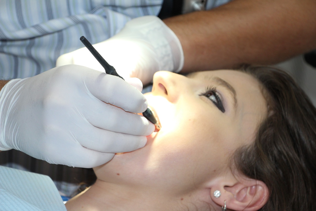 Woman lying down with dentist doing work inside her mouth